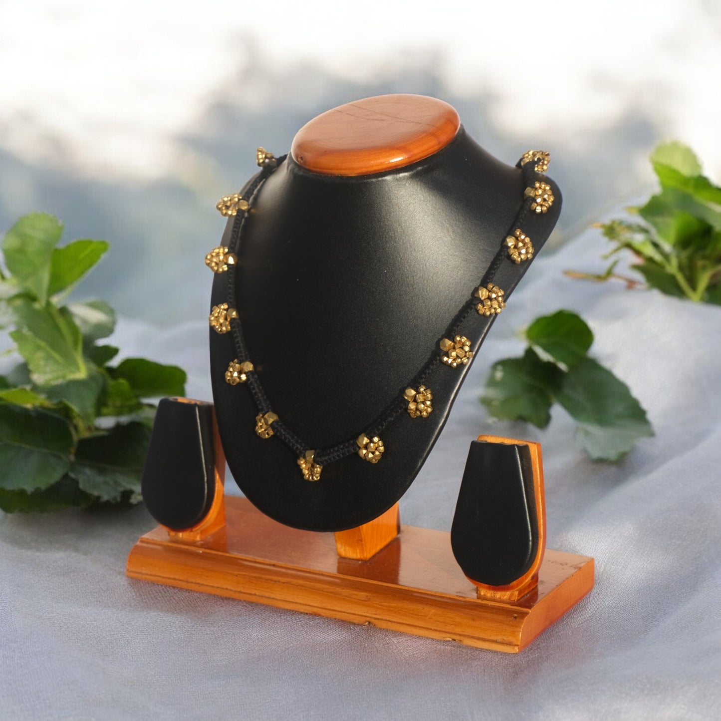 A black and gold Dhokra craft handmade Meena necklace displayed on a mannequin with a dark background, showcasing the necklace's design and brass details.