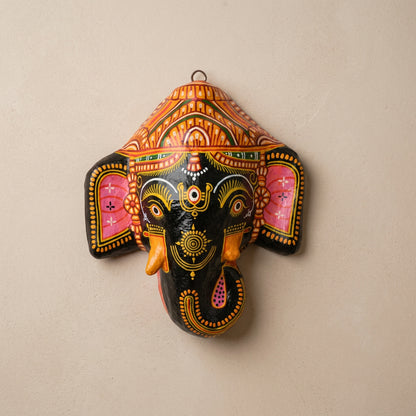 A colorful papier-mâché mask in the shape of Shree Ganesh with intricate details and patterns, displayed against a light background.